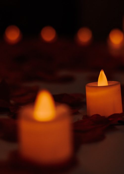 Cozy atmosphere with candles and rose petals creating a romantic ambiance.