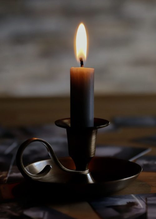 A warm, cozy scene with a lit candle surrounded by tarot cards on a wooden table, evoking a mystical atmosphere.