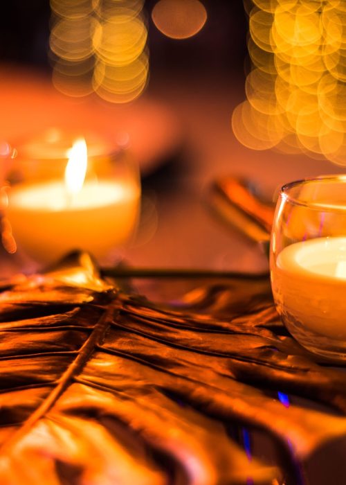 Glowing candles on a leaf with sparkling bokeh background create a warm, inviting atmosphere.