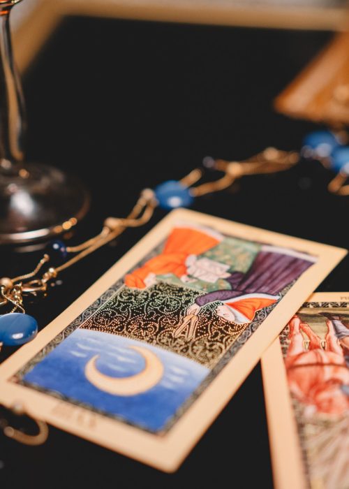 Close-up view of tarot cards on a table with a wineglass and mystical elements.